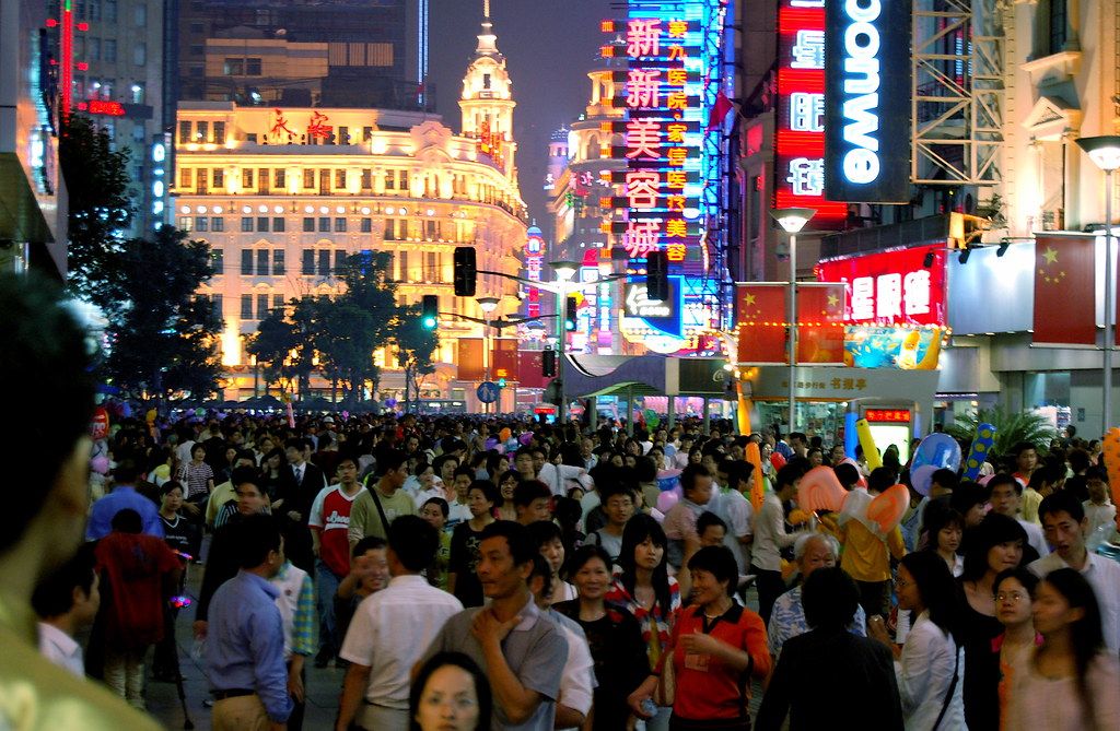 A traveler checking a smartphone on a busy Chinese city street