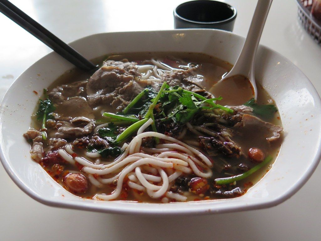 Bowl of Guilin rice noodles with crispy pork and pickled toppings