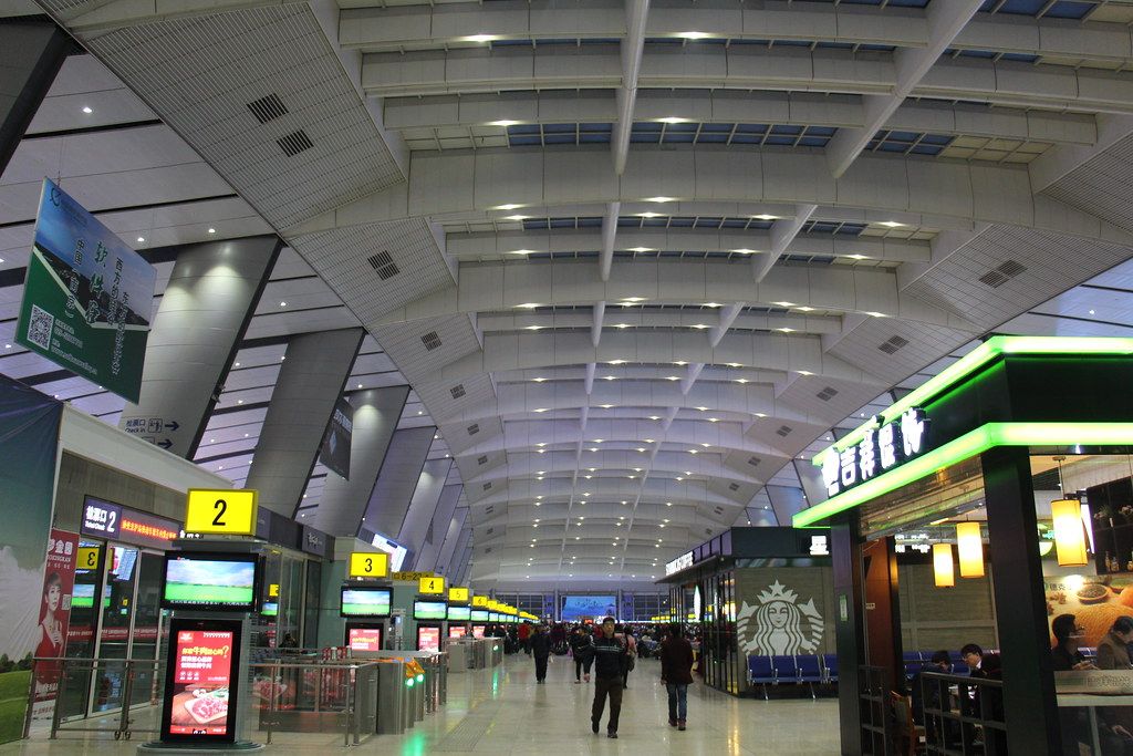 A modern Chinese railway station concourse with electronic departure boards