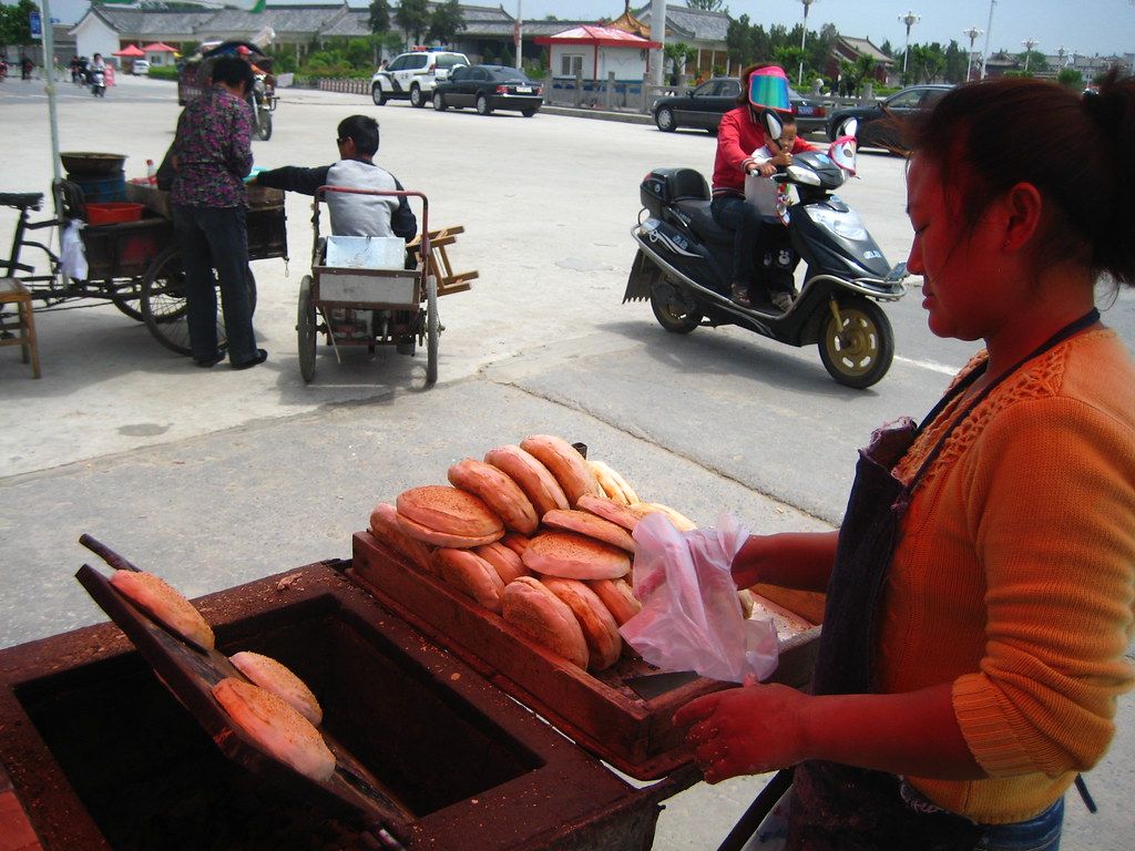 A busy Chinese street-food stall with steam and skewers